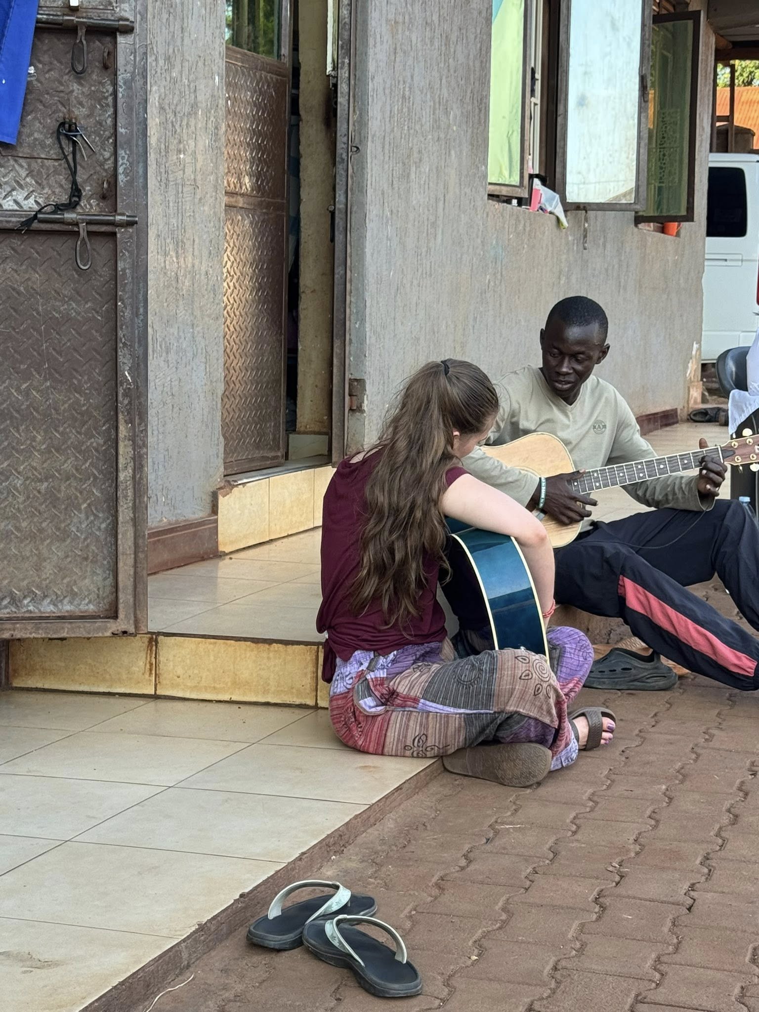 Claire playing guitar with an orphan at UOCC